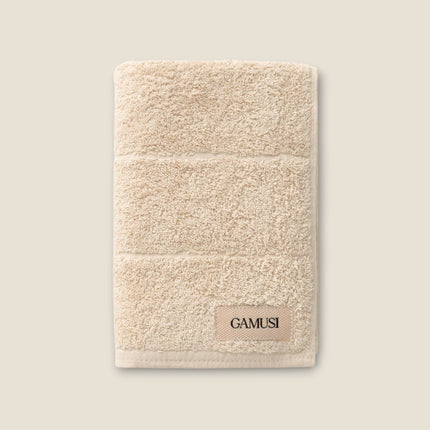 Madhome.ro beige cotton bath towel with a soft, plush texture and a decorative label detail.