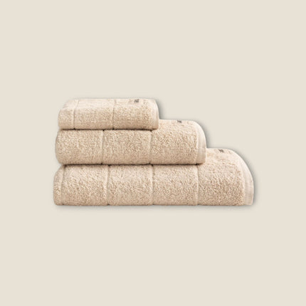Madhome.ro beige cotton towel set featuring three fluffy, absorbent towels of different sizes with reinforced edges.