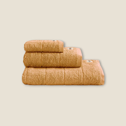 Madhome.ro set of three fluffy beige cotton bath towels stacked neatly on a white background
