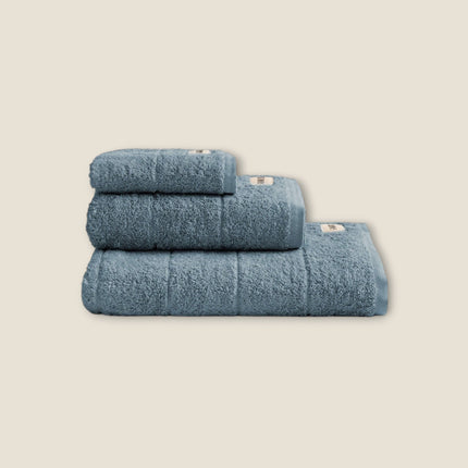 Madhome.ro set of three soft blue cotton bath towels stacked neatly, featuring a dense texture and elegant hem.