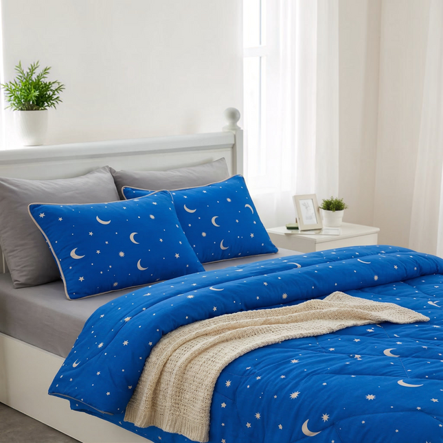Madhome.ro blue quilted bedding set with moon and star pattern, including a duvet and two pillows on a white bed.