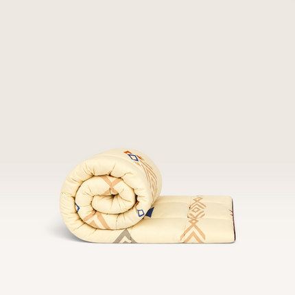 Madhome.ro Favorit quilted duvet rolled up, featuring a cream microfibre fabric with geometric blue and brown patterns.