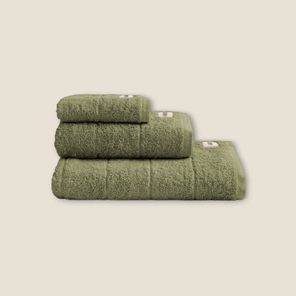 Madhome.ro set of three olive green cotton bath towels stacked neatly, featuring a soft, absorbent texture.