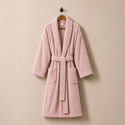 Madhome.ro pink cotton velour bathrobe with shawl collar, waist tie, and two pockets, hanging on a wall hook.