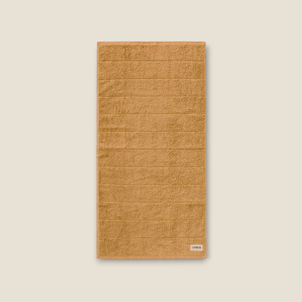 Madhome.ro soft tan cotton bath towel with a textured striped design and reinforced stitched edges