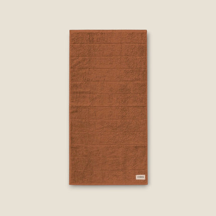 Madhome.ro soft terracotta cotton bath towel with a textured striped design and a small branded label