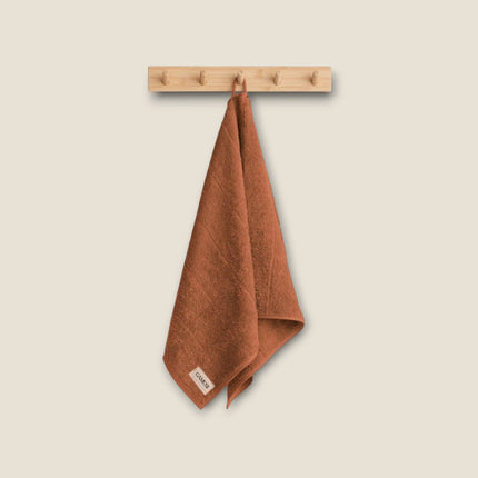 Madhome.ro soft terracotta cotton bath towel hanging on a wooden wall hook, featuring a dense, absorbent texture.