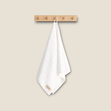 Madhome.ro white cotton bath towel hanging on a wooden wall hook, featuring a soft, absorbent, and plush texture.