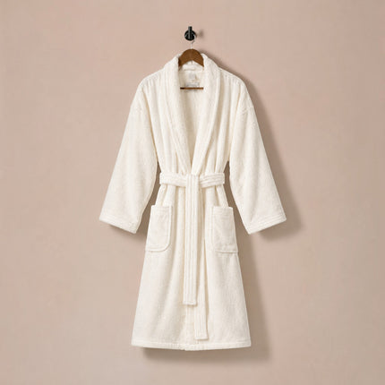Madhome.ro white 100% cotton velour bathrobe with shawl collar, waist belt, and two side pockets hanging on a hook.