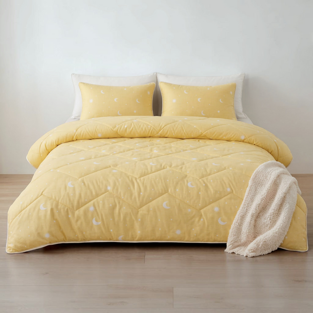 Madhome.ro yellow quilted bedding set with moon and star print, including a duvet and two matching pillows on a bed.